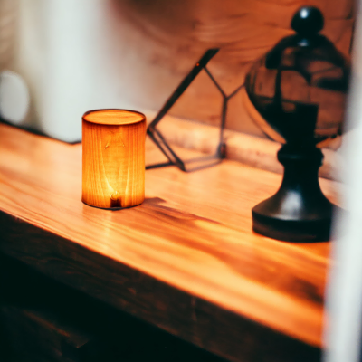 Lampe Sollia allumée et posée sur un meuble en bois massif